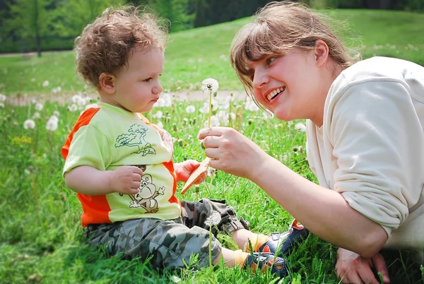 Smiling mother and son sitting on a field of flowers — Stock Photo, Image