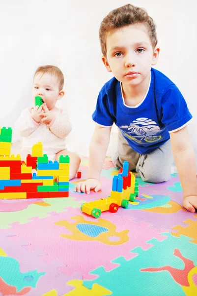 Liten flicka och pojke bygger ett hus av block — Stockfoto