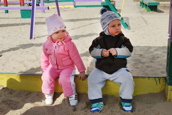 Хлопчик і дівчинка сидять у пісочниці — стокове фото