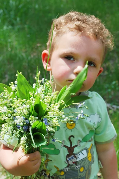 Niño con un ramo de lirios del valle — Foto de Stock