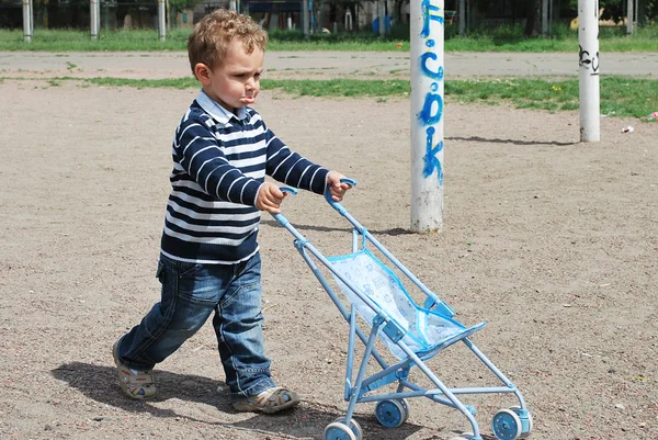 Liten pojke och flicka som leker med barnvagn. — Stockfoto