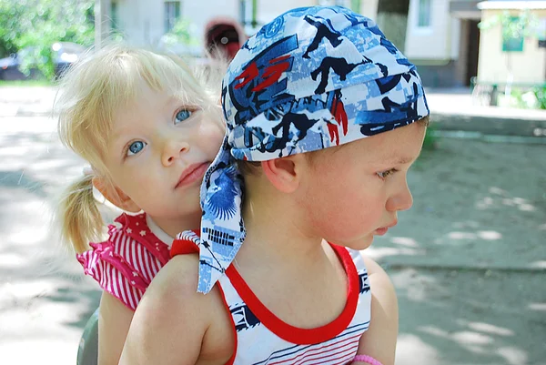 Kleines Mädchen umarmt einen Jungen, der in Gedanken sitzt — Stockfoto
