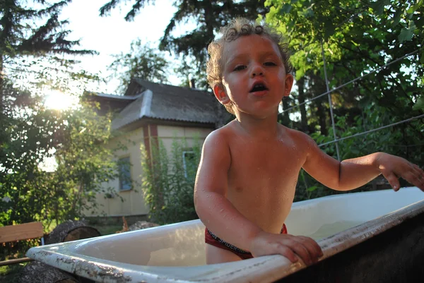 En las zonas rurales, al aire libre, el niño se baña en el baño, indulge i — Foto de Stock