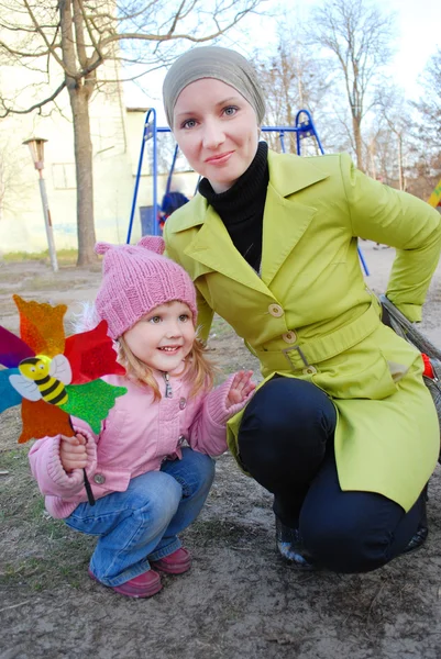 Chica con madre jugando con molino de viento — Foto de Stock
