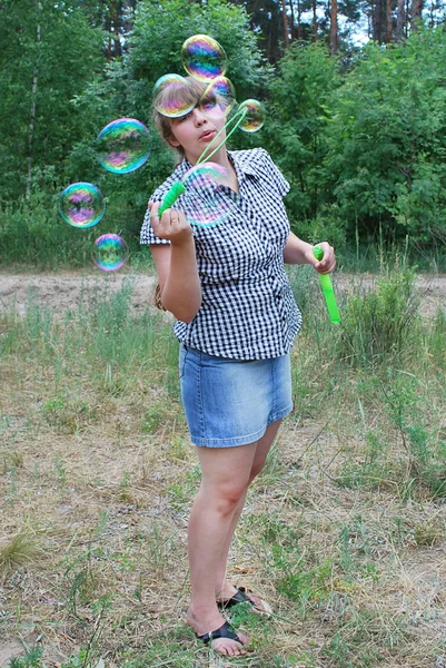 Flicka i skogen blåser såpbubblor — Stockfoto
