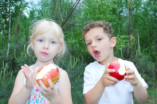 Little boy and girl are eating apples. — Stock Photo, Image