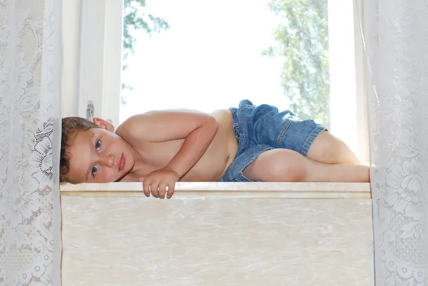 Lies on the windowsill sad resentful boy — Stock Photo, Image