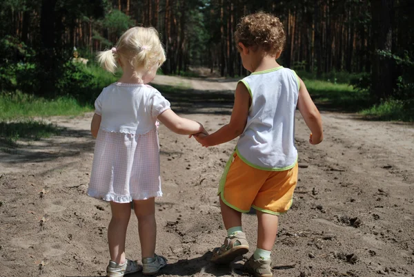 En el bosque a lo largo de la carretera son un niño y una niña sosteniendo — Foto de Stock