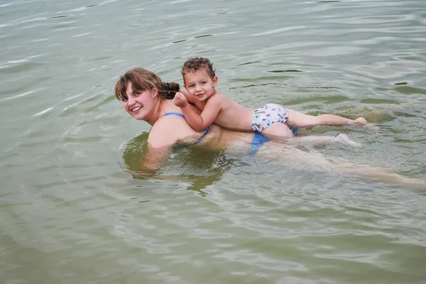 En el río, un niño con su madre flotando en el agua —  Fotos de Stock