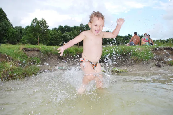 Liten pojke springer in floden, stänk överallt. — Stockfoto