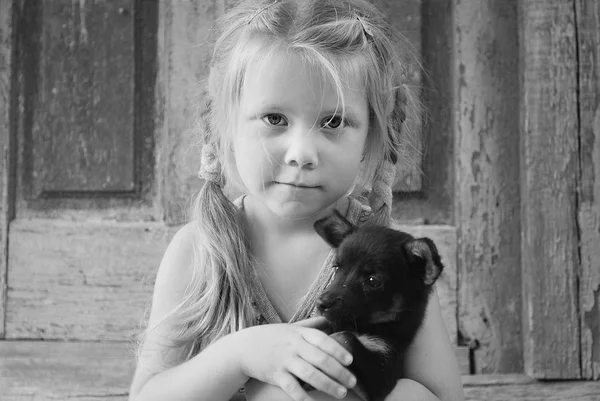 Una pequeña chica del pueblo sosteniendo un perro — Foto de Stock