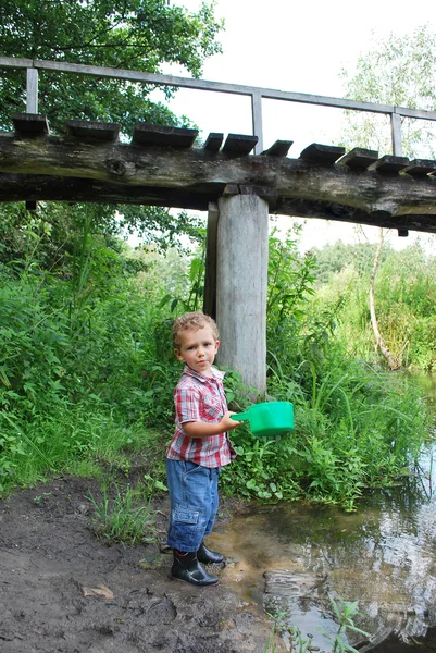 Outdoors, near the river and bridges, the little boy is playing — Stock Photo, Image