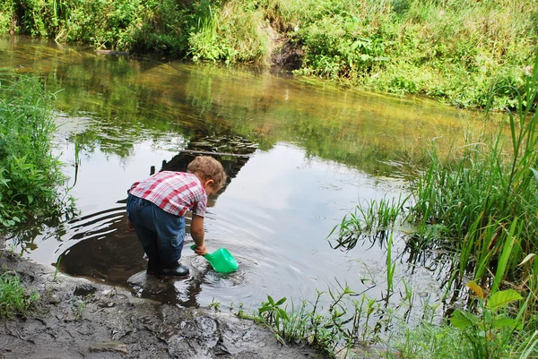 All'aperto, vicino al fiume e ai ponti, il bambino sta giocando — Foto Stock