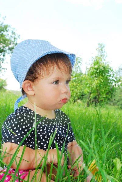 Small, funny girl sitting in the grass — Stockfoto