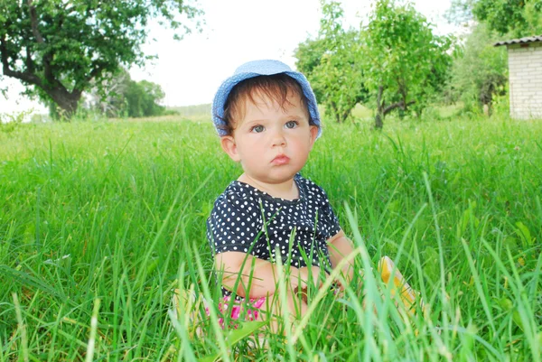 Small, funny girl sitting in the grass — Stock Photo, Image