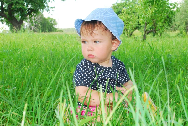 Menina pequena e engraçada sentada na grama — Fotografia de Stock