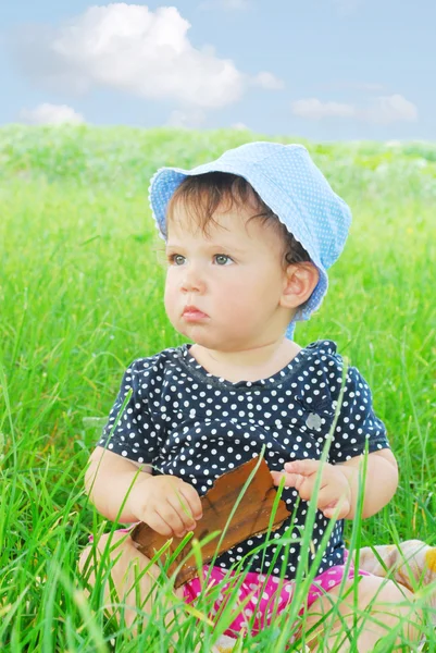 Menina pequena e engraçada sentada na grama — Fotografia de Stock