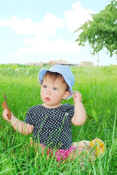 Small, funny girl sitting in the grass — Stock Photo, Image