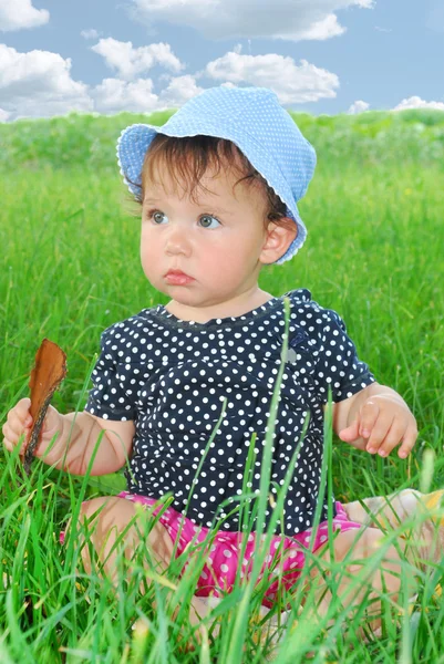 Malé, legrační dívka sedící v trávě — Stock fotografie