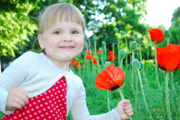 Pequeña, chica divertida se para cerca de amapolas —  Fotos de Stock