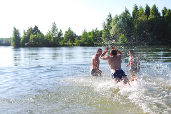 Влітку хлопчики плавають в озері, пірнають, плескають Ліцензійні Стокові Зображення