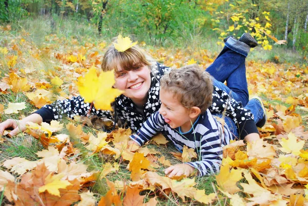 In the forest, mother lies on the grass and hugging her son, th — Stock Photo, Image