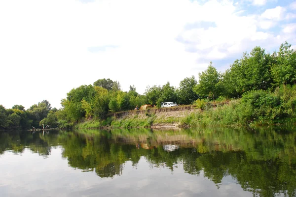 El río, sobre un acantilado, la gente estableció el campamento . — Foto de Stock