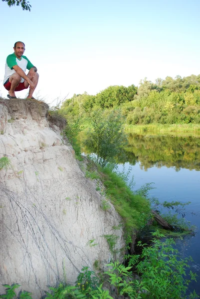 在夏天，在河边，悬崖，坐在一个男人. — 图库照片