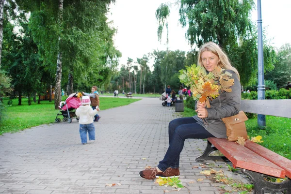 公園のベンチとイエローの花束を保持している女の子に座っています。 — ストック写真