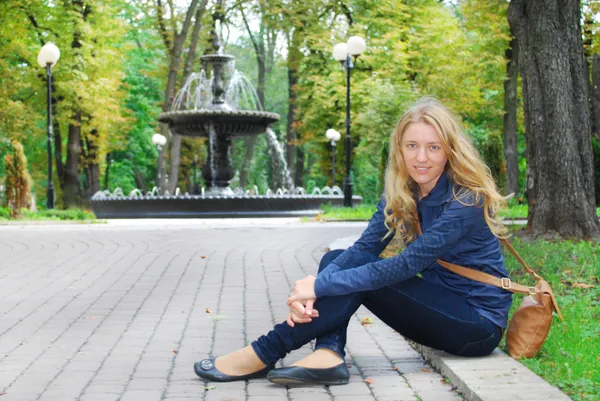 분수 근처 공원에서 소녀 보도에 앉아. — 스톡 사진