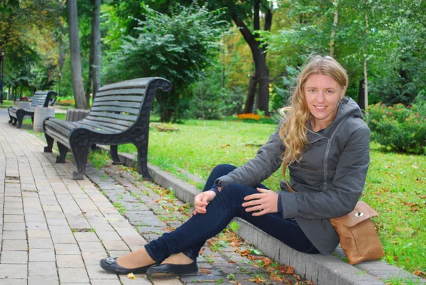 In het park, het meisje dat zit op de stoep — Stockfoto