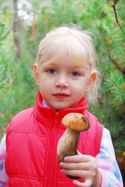In the forest, the little girl is holding a mushroom boletus. — Stock Photo, Image