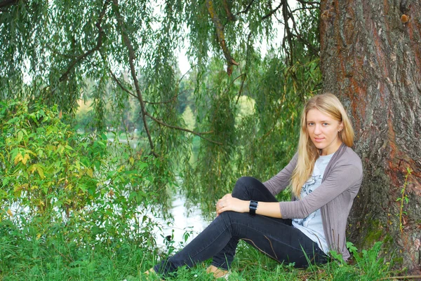 Dziewczyna siedzi w pobliżu wierzby w pobliżu jeziora. — Zdjęcie stockowe