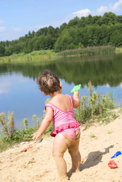 Sur la plage près du lac dans le sable petite fille jouer avec — Photo