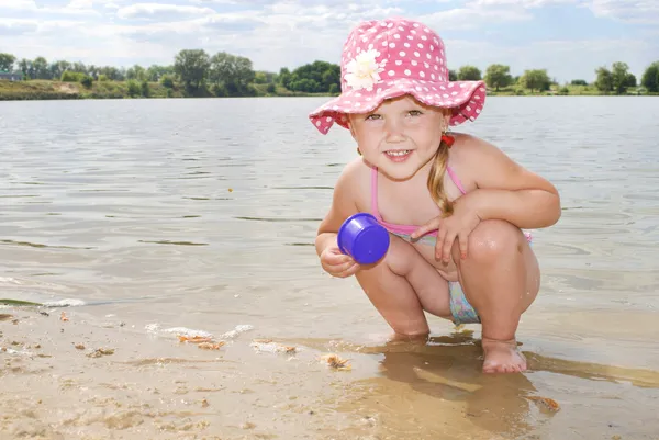 Plaża nad jeziorem w piasek mały dziewczyna w kapeluszu pogrywam — Zdjęcie stockowe