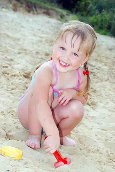 Na praia perto do lago na areia menina brincando com — Fotografia de Stock