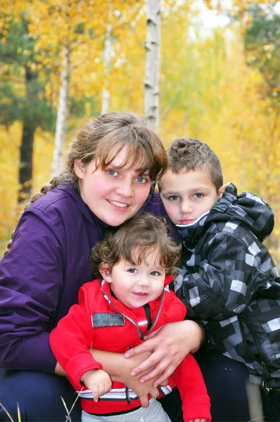 In the autumn forest mother hugging daughter and son. — Stock Photo, Image