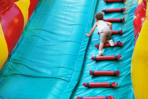 Kleiner Junge spielt auf einem aufblasbaren Spielplatz — Stockfoto