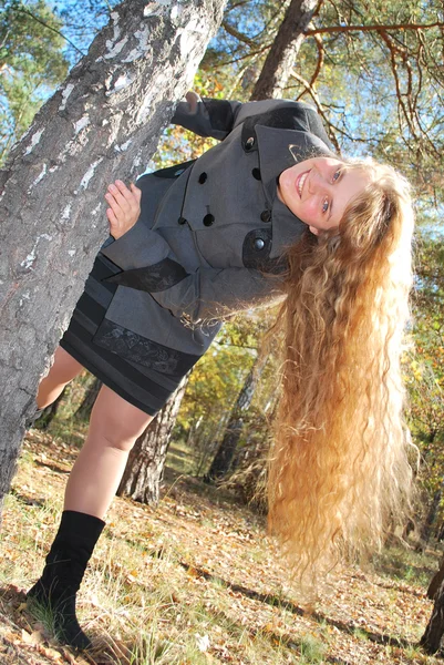 En vacker flicka med långt lockigt hår, kikar ut bakifrån — Stockfoto