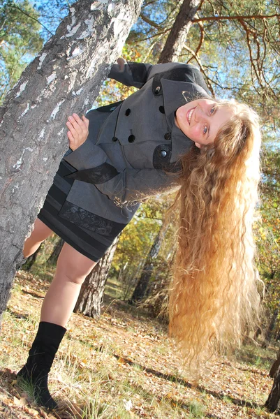 A beautiful girl with long curly hair, peeking out from behind — Stock Photo, Image