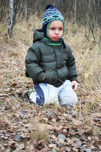 I skogen sitter på gräset ledsen upprörd pojke — Stockfoto