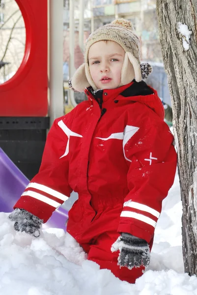 Зимовий хлопчик грає на снігу біля дитячого майданчика . — стокове фото
