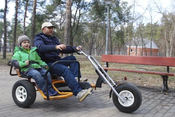 Far och son dubbel cykeltur i parken under våren — Stockfoto