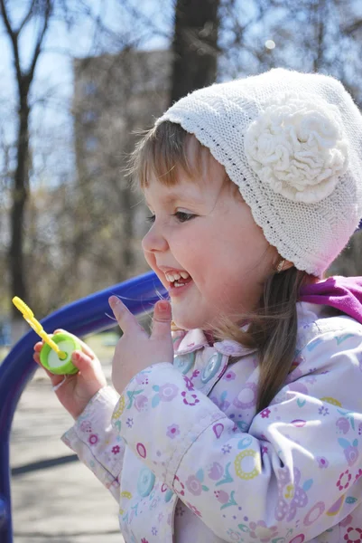 En liten flicka som leker på lekplatsen och skrattar. — Stockfoto