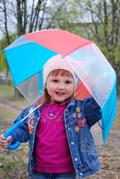 Der Park ist ein kleines Mädchen unter einem Regenschirm. Stockfoto