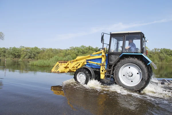 Tracteur à travers la rivière qui est sorti de ses rives et inondé — Photo