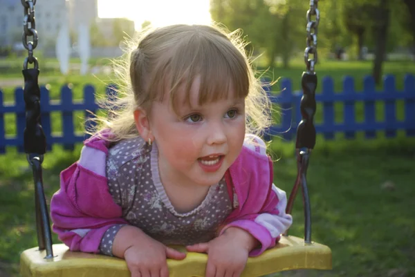 Een klein meisje spelen op de speelplaats en lacht. — Stockfoto