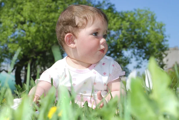 Kleine Mädchen sitzen in einem Feld Löwenzahn. — Stockfoto