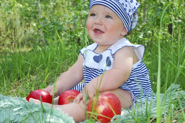 Menina senta-se em um bétula na grama e come uma maçã — Fotografia de Stock