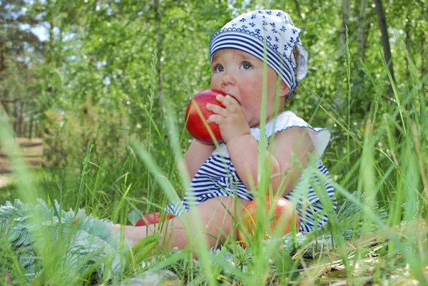 Girl sits in a birchwood on the grass and eats an apple — Stock Photo, Image